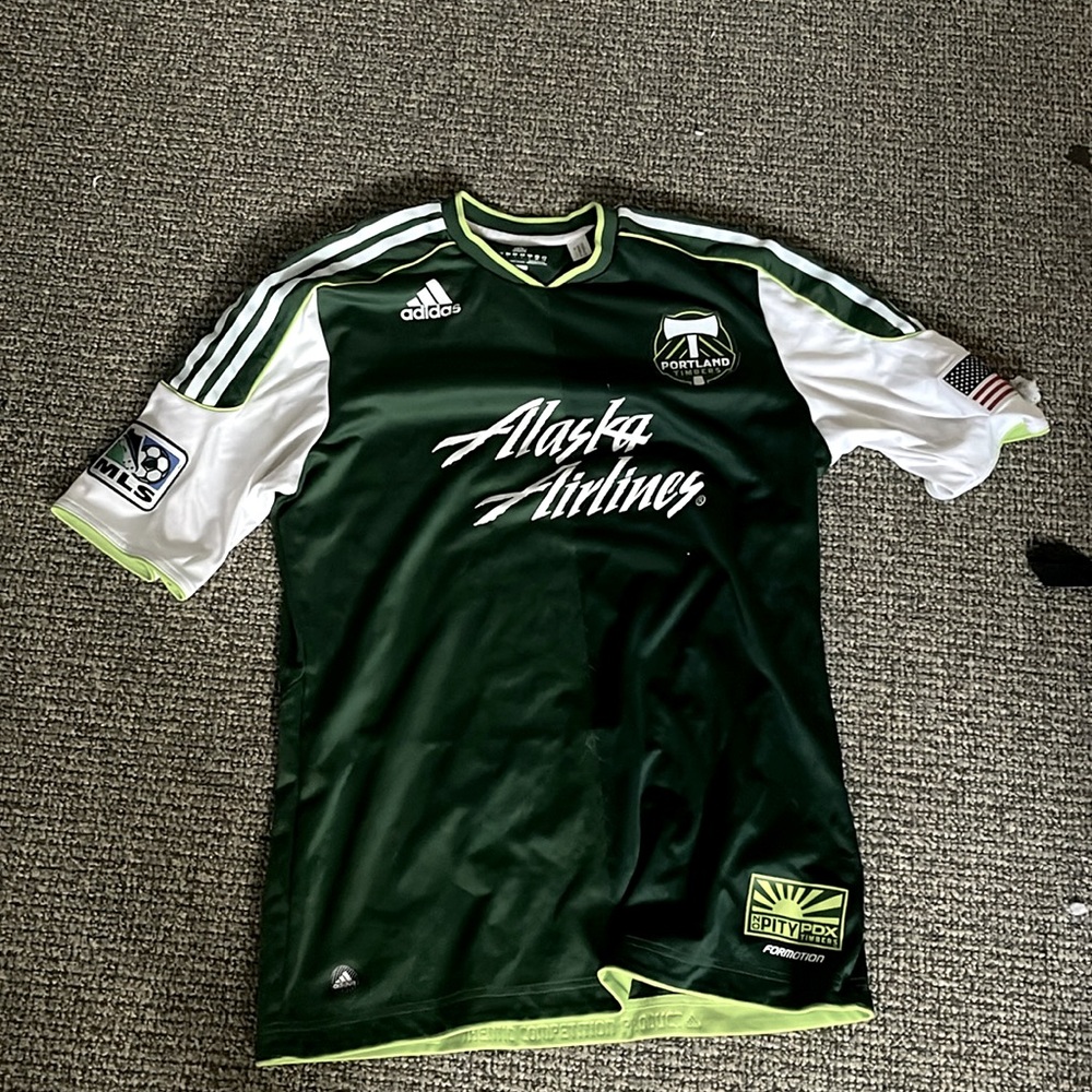 An Green Adidas shirt with Alaska airlines written on it.